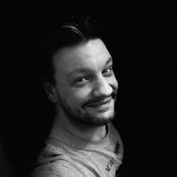 Portrait of young man against black background