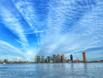 Sea by modern buildings against sky