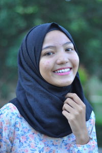 Portrait of smiling teenage girl against trees