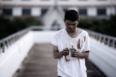 Young man holding camera while standing outdoors