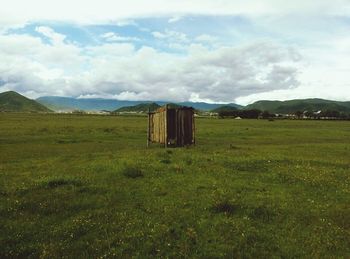 Scenic view of grassy field against cloudy sky