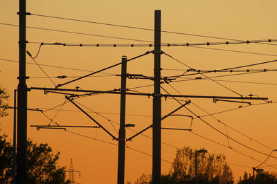 Public transportation electrical lines used for tramway upon golden hour orange sky