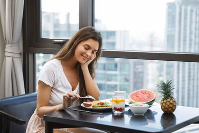 Portrait of young woman sitting on table at home