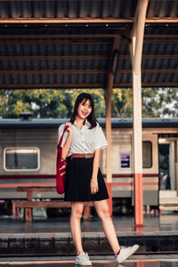 Portrait of smiling woman standing at railroad station platform