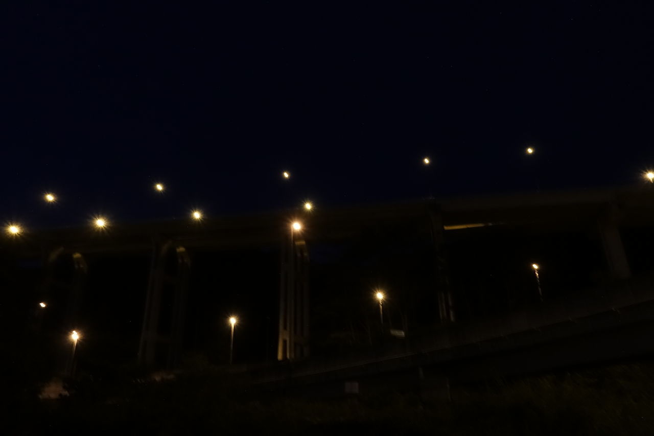 ILLUMINATED STREET LIGHTS AGAINST SKY AT NIGHT