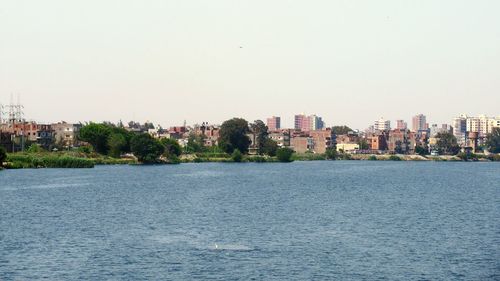 Scenic view of sea by buildings against clear sky