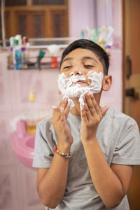 Portrait of boy holding camera at home