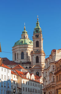 Low angle view of clock tower with the dome of st nicholas cathedral on lesser town square.