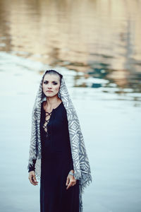 Woman looking away while standing by sea