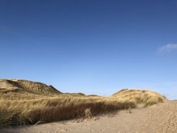 Scenic view of desert against clear blue sky