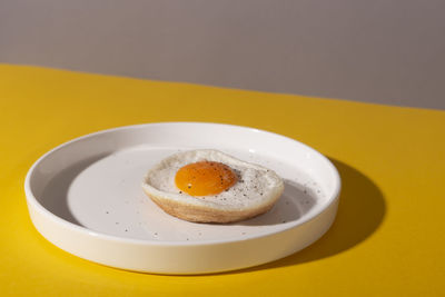 Zine styled creative round plate with fried egg on a yellow table with hard shadows.