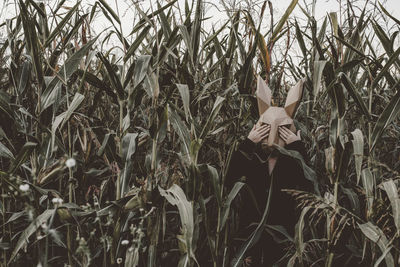 Woman wearing mask while standing amidst plants