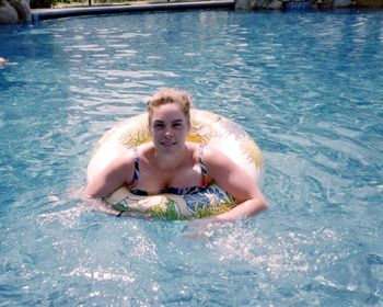 Portrait of smiling mature woman with inflatable ring swimming in pool