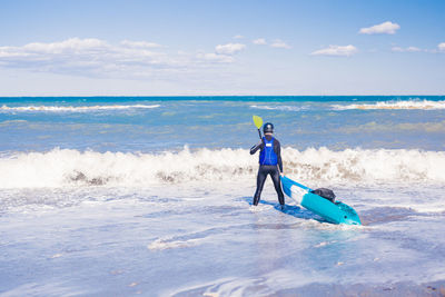 Rear view of man standing in sea against sky