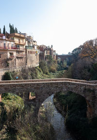 Arch bridge over river against buildings