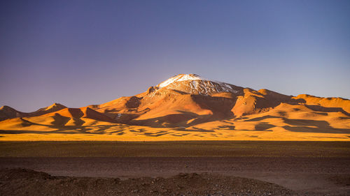 Scenic view of desert against clear blue sky