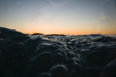 Surface level of sea against sky during sunset