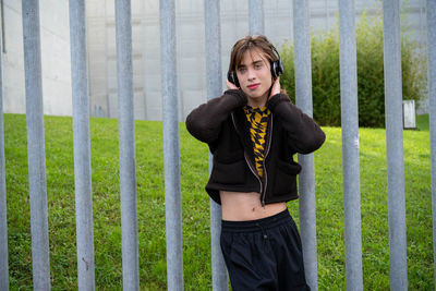 Young woman standing against fence