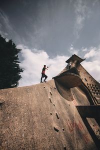 Low angle view of boy standing on metallic structure against sky