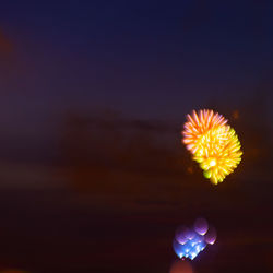 Close-up of hand holding illuminated lights against sky