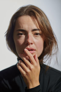 Close-up portrait of young woman against white background