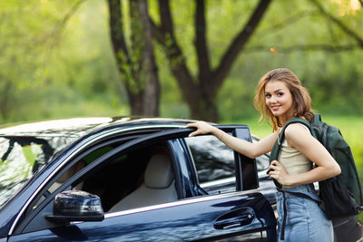 Portrait of smiling young woman standing in car