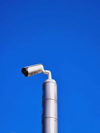 Low angle view of security camera against blue sky