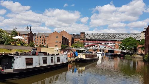 Bridge over river by buildings in city against sky