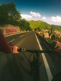 Man riding bicycle on road against sky