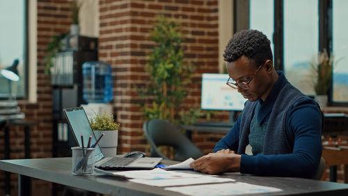 Side view of man using laptop at office