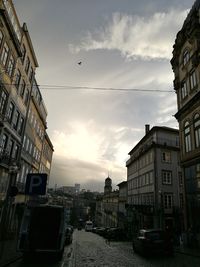 Cars on street in city against sky