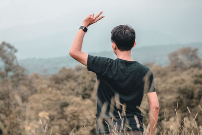 Rear view of man standing on field against sky