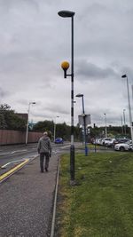 People on road against cloudy sky