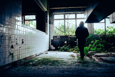 Rear view of man walking in abandoned building