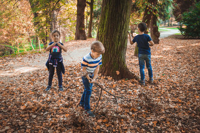 Happy siblings playing in park on autumn leaves