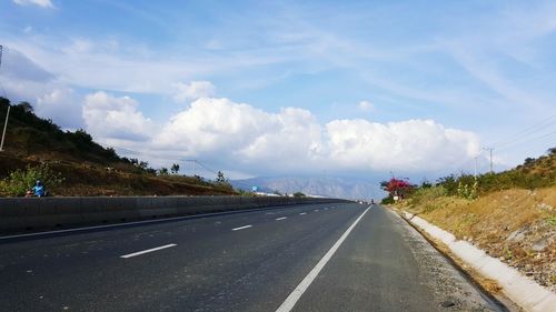 Road by mountains against sky