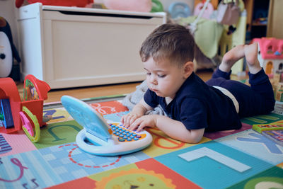 Curious little toddler playing with his toy computer