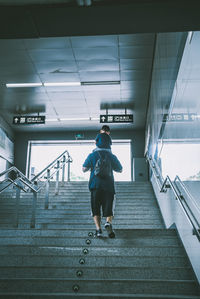 Rear view of man walking on staircase