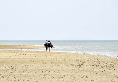 People on beach against clear sky