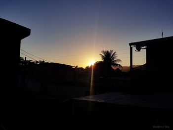 Silhouette houses against sky during sunset