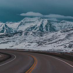 Diminishing perspective of road by snowcapped mountain against sky