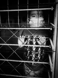 Portrait of woman seen through metal fence