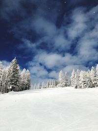 Snow covered landscape against cloudy sky