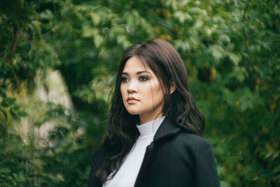 Beautiful woman looking away against trees