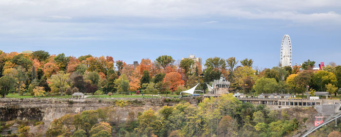 Bridge over river amidst trees and buildings against sky