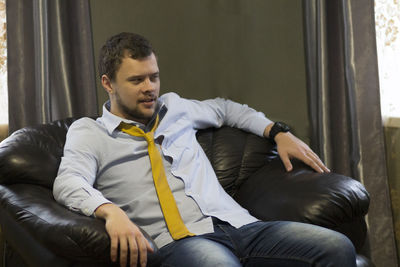 Young man looking at camera while sitting on sofa