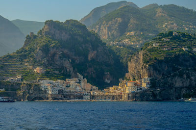 Scenic view of sea by mountain against sky