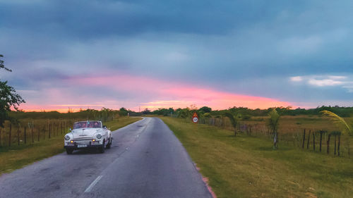 Cars on road amidst field against sky