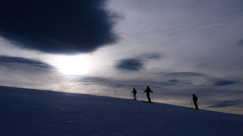 Silhouette of people on a ski tour on snowcapped mountain against sky