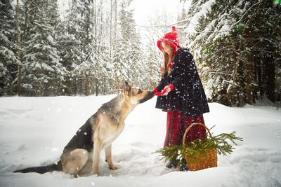 Portrait of woman with dog on snow covered field